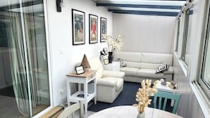 A modern living room with a white sofa, a round table, and a glass wall.