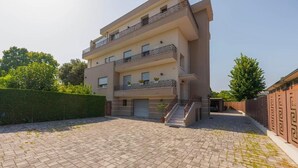 Un edificio residencial de varios pisos con un patio empedrado, balcones con barandillas y una escalera que lleva a la entrada.