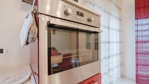 Un horno de acero inoxidable con pantalla digital, puerta roja y una ventana de cocina.
