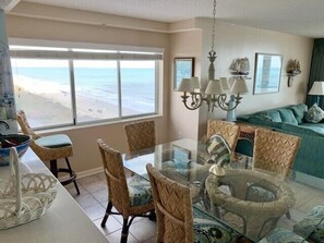 A dining area with a glass table, wicker chairs, and a view of the beach. - 4BR OF Windy Hill beauty! Dream rental. Great amenities! (North Myrtle Beach)