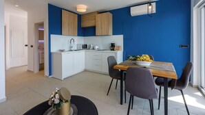Une cuisine moderne avec des meubles blancs, une table à manger en bois et un mur d’accent bleu.