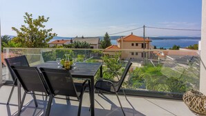 Un balcon avec une table et des chaises, donnant sur un quartier résidentiel et un plan d’eau.