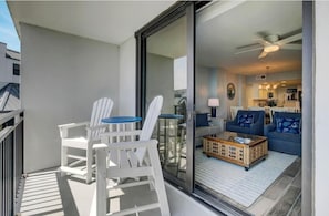 Ein Balkon mit weißen Adirondack-Stühlen und einem Korbtisch.