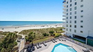 Un hotel con piscina, vista sulla spiaggia e un edificio a più piani.