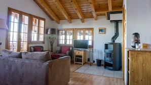 Ein Wohnzimmer mit Holzboden, einem Fernseher auf einem Holzständer, einer Couch und einem Kamin.