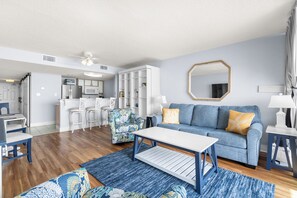 Ein modernes Wohnzimmer mit einem blauen Sofa, einem Couchtisch und einem gemusterten Teppich.