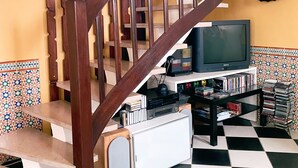 A staircase with wooden railings, a television on a stand, and a wall clock. - Seaside Holiday Home: Spacious, Welcoming, Garden, Wi-Fi (Pornic)