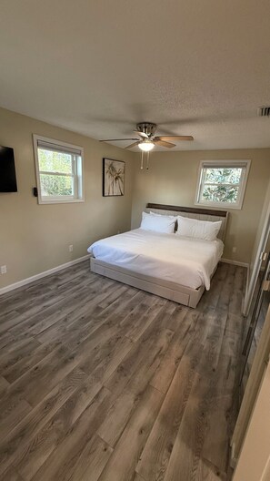 A bedroom with a bed, two windows, a ceiling fan, and wooden flooring. - Stunning Mobile Bay views near Dauphin Island (Coden)