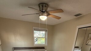 A bedroom with a bed, wooden flooring, a ceiling fan, and a window. - Stunning Mobile Bay views near Dauphin Island (Coden)