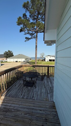A wooden deck with a table and chairs, overlooking a grassy area and a body of water. - Stunning Mobile Bay views near Dauphin Island (Coden)