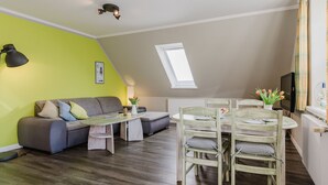 Ein modernes Loft-Apartment mit Essbereich, einer Sofagarnitur, einem kleinen Tisch und einem Fernseher.