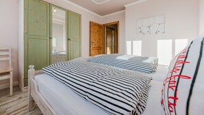 Ein Schlafzimmer mit einem Bett, einem grünen Kleiderschrank, einer Holztür und einer Wand mit einem Löwenzahnmuster.