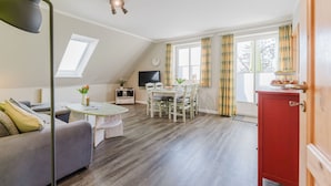 Ein gemütliches Wohnzimmer mit einer Couch, einem Esstisch mit Stühlen, einem Fernseher und einem roten Schrank.