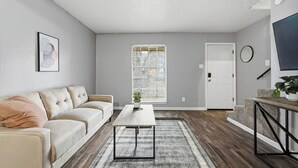 Una sala de estar con sofá, mesa de centro y una puerta.