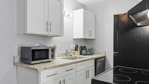 A kitchen with white cabinets, a black stove, a microwave, and a coffee maker. - Comfortable 1BR townhome with full kitchen (Arlington)