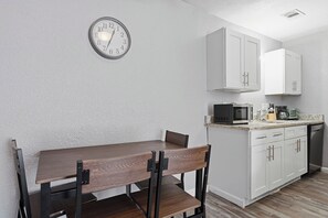 A compact kitchen with white cabinets, a microwave, and a coffee maker on the countertop. - Comfortable 1BR townhome with full kitchen (Arlington)
