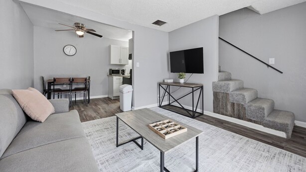 A modern living room with a sofa, coffee table, and a dining area with chairs and a table. - Comfortable 1BR townhome with full kitchen (Arlington)