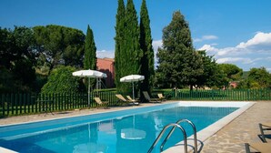A swimming pool with lounge chairs and umbrellas, surrounded by a green fence and tall trees. - Lovely room for 4 people with A/C, pool, WIFI, TV, veranda and pets allowed, close to Perugia (Agello)