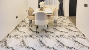 Un menjador modern amb sòl de marbre, taula blanca i cadires beix.