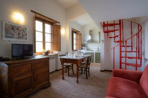 A kitchen with a dining table, chairs, and a red spiral staircase. - Cosy room with WIFI, pool, A/C, TV, patio, pets allowed and panoramic view, close to Perugia (Agello)