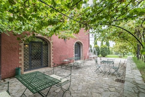 A courtyard with stone flooring, outdoor seating, and a brick building with arched windows. - Cosy room with pool, A/C, WIFI, TV, patio, pets allowed and panoramic view, close to Perugia (Agello)