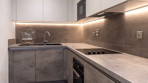 A modern kitchen with a built-in stove, a sink, and a microwave. - Round The Clock Bookings - Wharf 1ne (Barking)