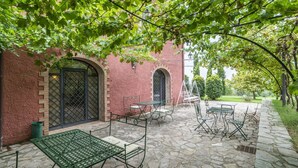 A courtyard with stone flooring, outdoor seating, and a red brick building with arched windows. - Nice room for 2 guests with A/C, WIFI, pool, TV, veranda and pets allowed, close to Perugia (Agello)