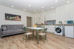 A compact living space with a sofa, dining table, chairs, a washing machine, and a microwave. - 'Vitali Home' - Apartment in the Heart of Catania (Catania)