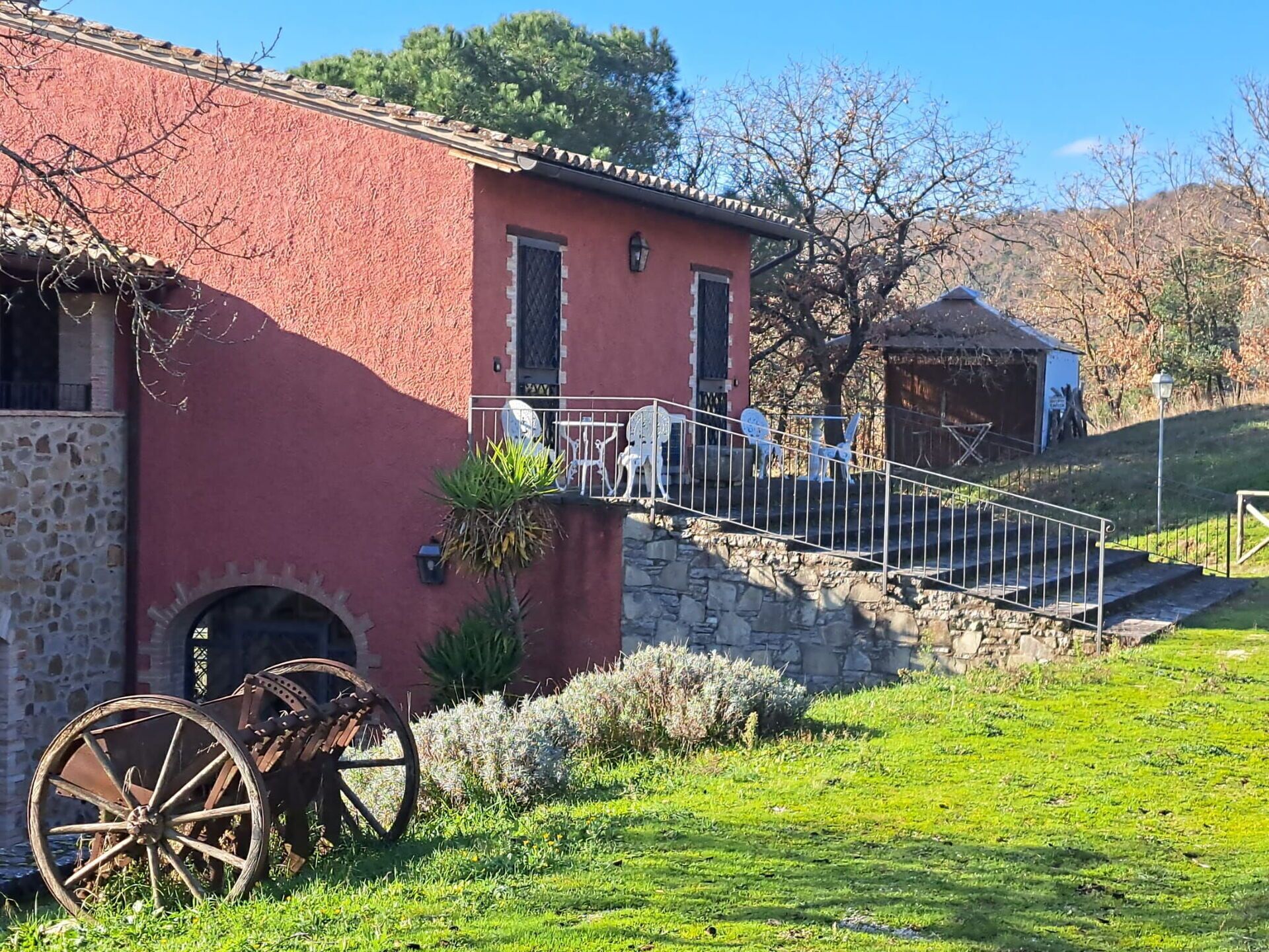 Un edificio rosso con muro in pietra, una scala e un carretto.
