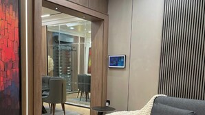 Een moderne kamer met een bank, een glazen deur naar een eethoek en een lijst met een afbeelding aan de muur.