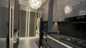 Een moderne keuken met roestvrijstalen apparatuur, een centraal keukenblok en hangende lampen.
