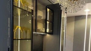 Een modern interieur met een glazen kast, een kroonluchter en een eethoek met stoelen.