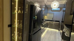Een moderne keuken met roestvrijstalen apparatuur, een glazen wijnrek en hanglampen.