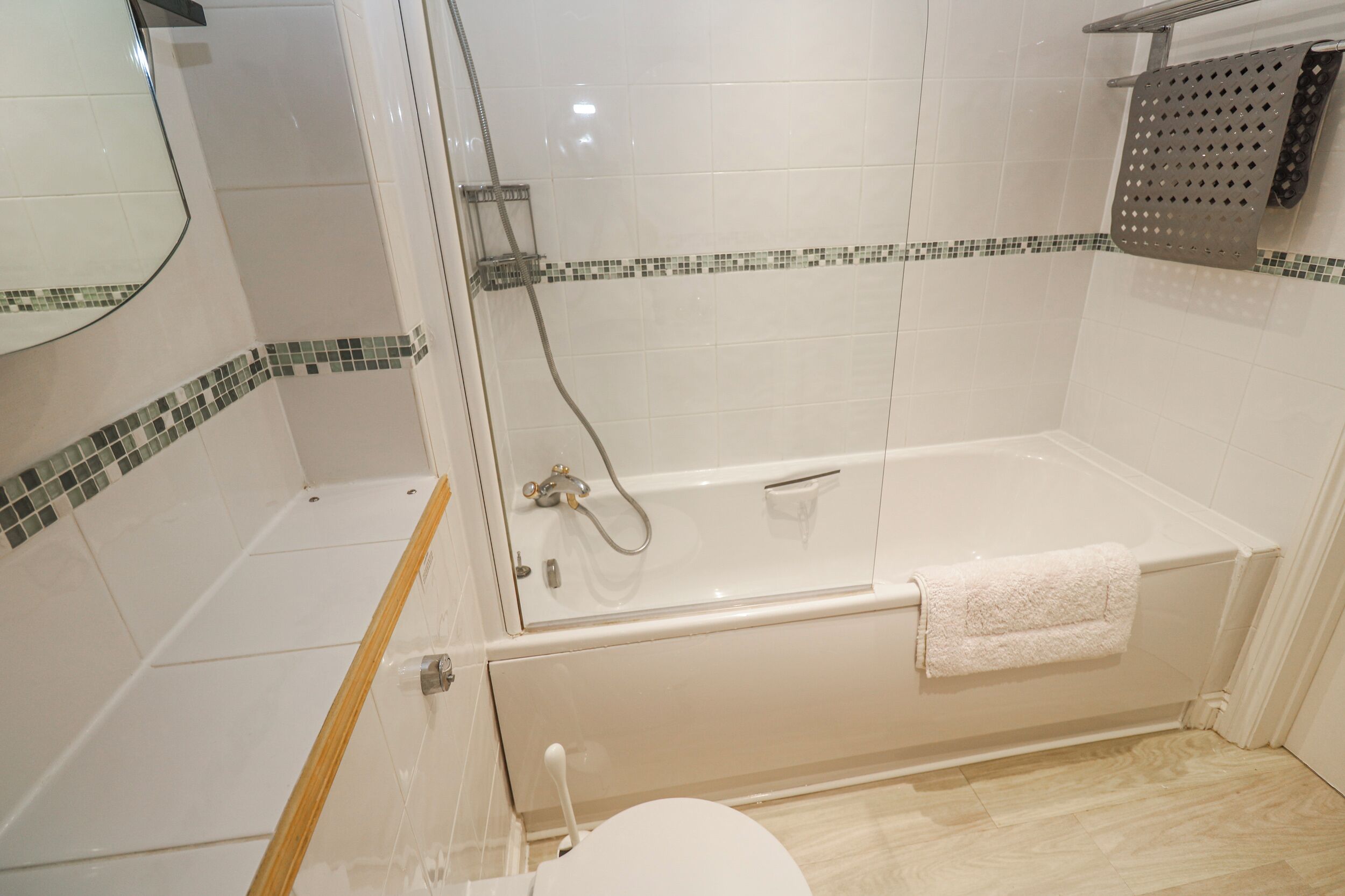 A bathroom with a glass-enclosed shower, a bathtub with a towel, and a toilet.