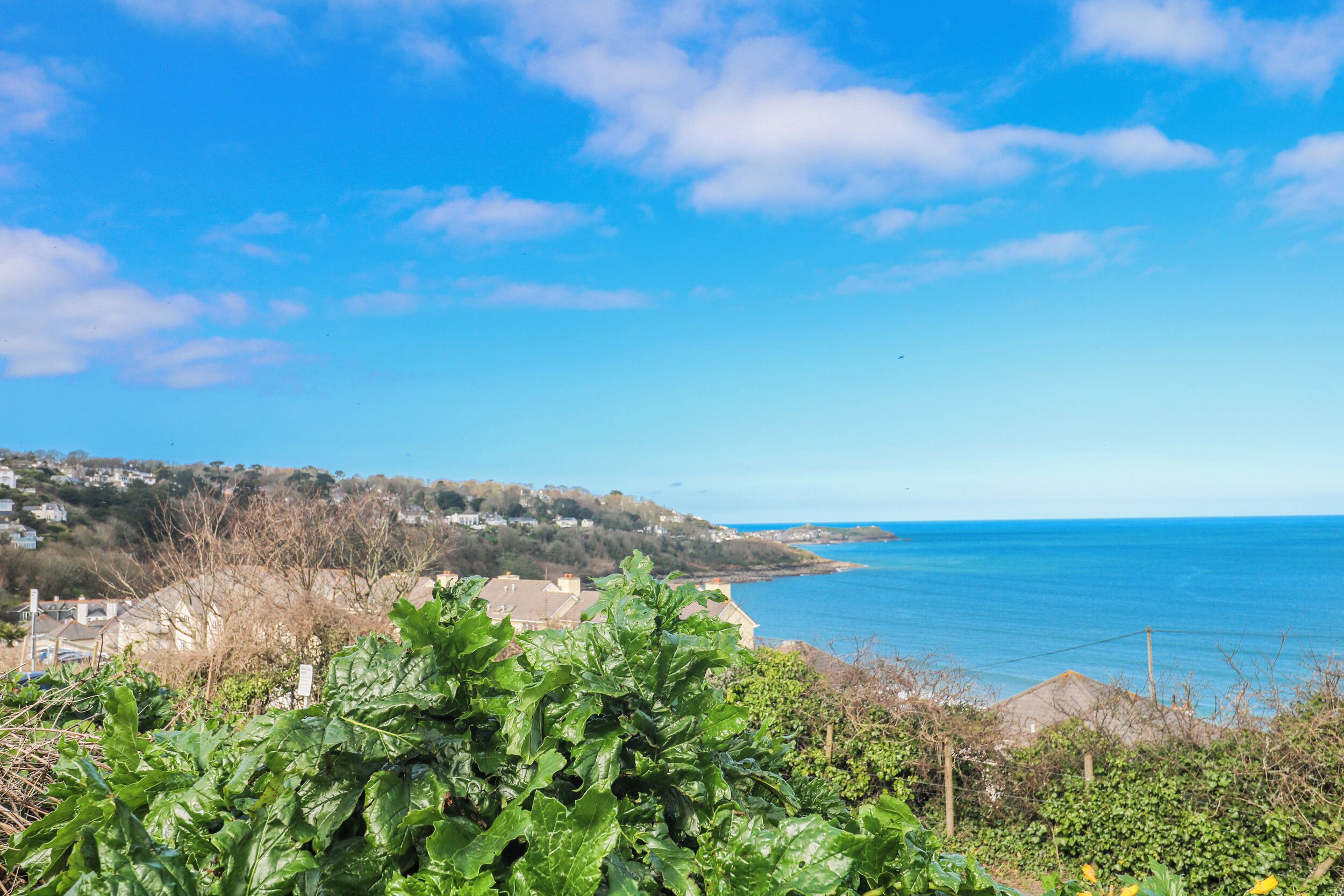 A coastal landscape with houses, a clear sky, and the sea.