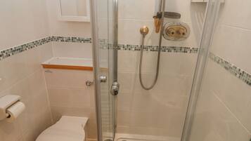 A shower with a glass door, a toilet, and a towel rack.