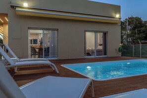A modern building with a swimming pool, lounge chairs, and a dining area. - Villa Variana | villa with private pool in Kifisia (Kifisia)