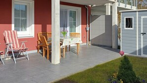 Un patio con mobiliario exterior, una mesa con mantel floral y un cobertizo.