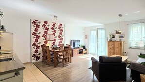 Un apartamento moderno con comedor, cocina, sala de estar y un ventanal grande.