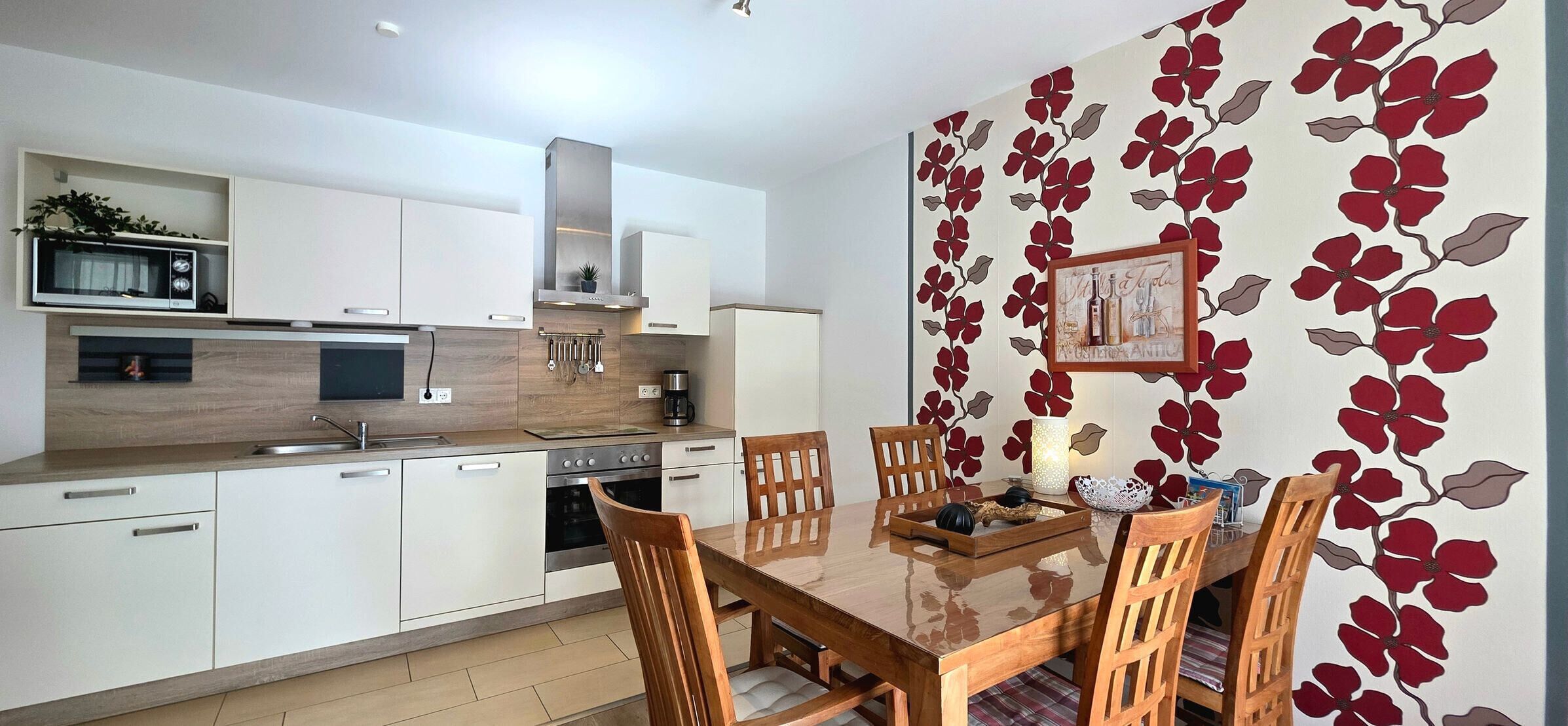 A modern kitchen with white cabinets, a microwave, stove, and a dining area with a wooden table and chairs.