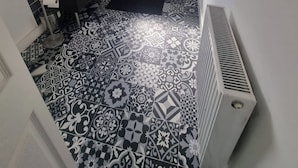 Une salle de bain avec une baignoire, une fenêtre, un lavabo et un radiateur.