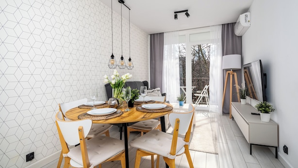 A dining area with a round table, chairs, and a chandelier. There is a sofa and a TV in the background. - Apartamenty Sun & Snow Miodowa (Warsaw)