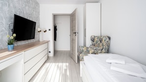 A bedroom with a bed, a TV, a desk, and a chair. - Apartamenty Sun & Snow Miodowa (Warsaw)