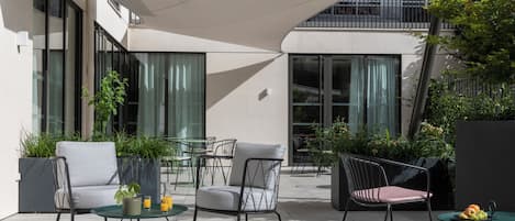 An outdoor seating area with modern chairs, tables, and potted plants.