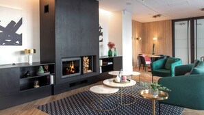 Una sala de estar moderna con chimenea, mesas de centro redondas y un sofá verde.