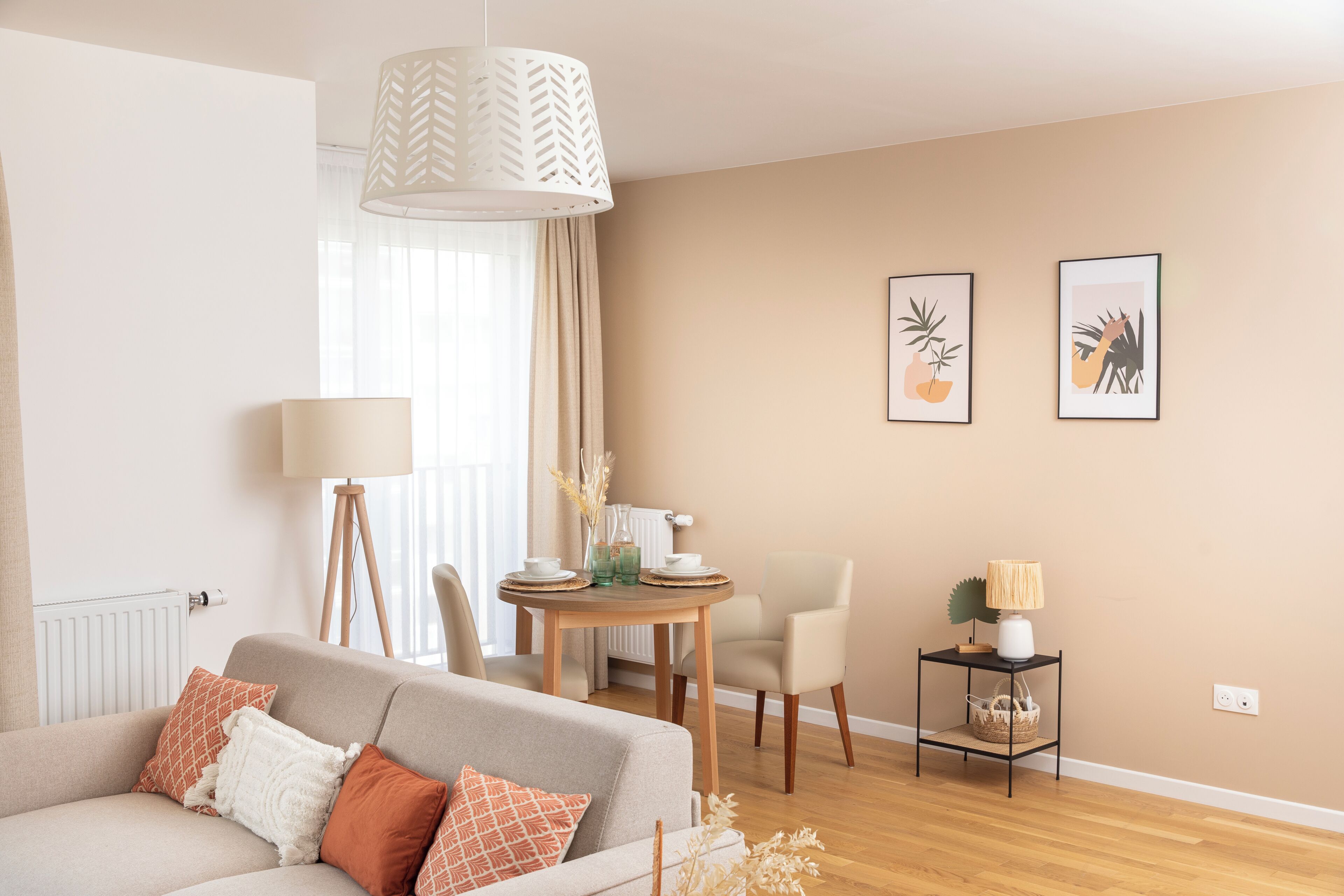 Ein Wohnzimmer mit einer Couch, einem Esstisch, Stühlen, einer Lampe und Wandbildern.