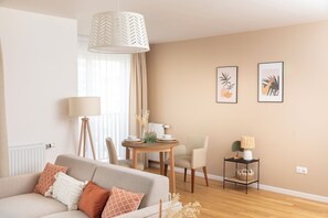 Ein Wohnzimmer mit einer Couch, einem Esstisch, Stühlen, einer Lampe und Wandbildern.
