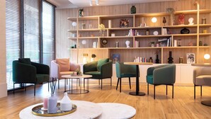 Un interior moderno con piso de madera, una estantería y sillas verdes y blancas.