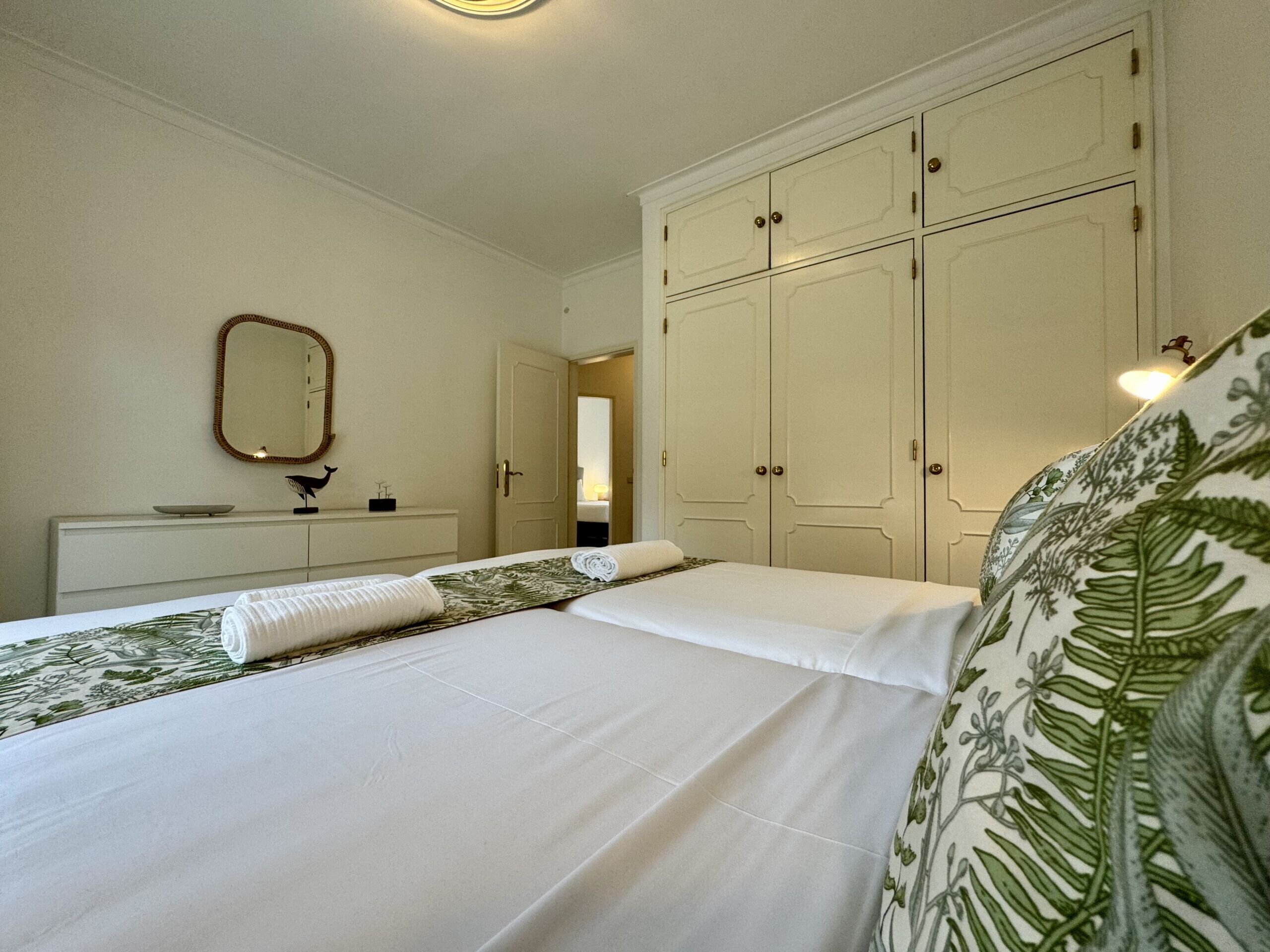 Una habitación de hotel con una cama, un tocador, un espejo y un armario.
