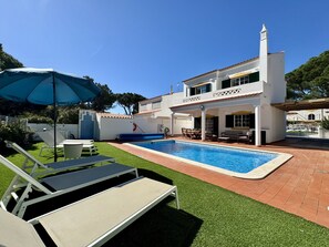 A poolside area with a swimming pool, lounge chairs, and a covered patio. - Vilamoura Summer Villa 3 by Homing (Loulé)